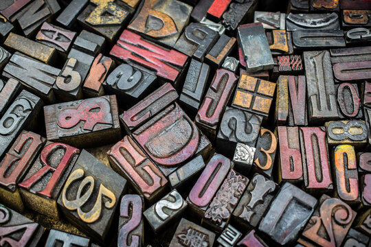 A textured background of old, used, wooden type-setting letter blocks with various fonts, upper- and lowercase, antique letters, all shapes and sizes. 
