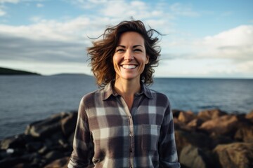 Portrait of a smiling woman in her 40s wearing a comfy flannel shirt against a stunning ocean reef. AI Generation