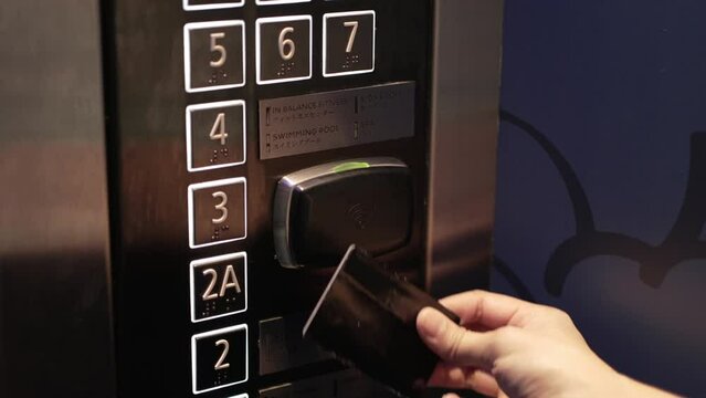 Close up hand of woman using proximity card, contactless digital key to unlock for use elevator in the hotel. Digital or keyless to authenticate.