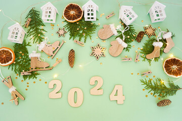 Wooden Christmas toys, thuja branches and dried orange slices on a green background with numbers...