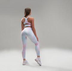 sexy athletic girl in a tight fitness tracksuit on a light background copy paste in the studio