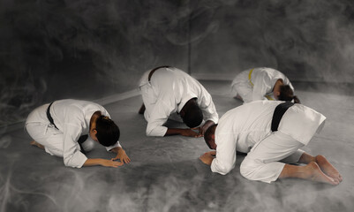Teacher coach of martial arts and students followers sit on floor and make ritual obedience bows...