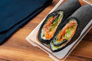Black tortilla wrap with salted salmon and vegetables