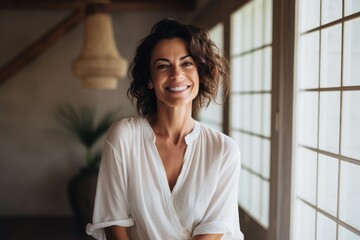 Portrait of a happy woman in her 40s wearing a simple cotton shirt against a serene meditation room. AI Generation