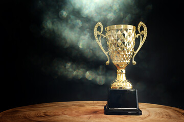 Image of trophy over wooden table and dark background, with abstract shiny lights - obrazy, fototapety, plakaty