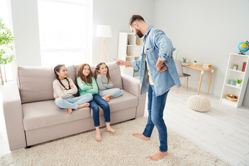 Full size photo of four people guy standing pointing finger cheerful small girls sitting on couch...