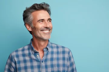 Fotobehang Portrait of a glad man in his 50s wearing a comfy flannel shirt against a pastel blue background. AI Generation © CogniLens