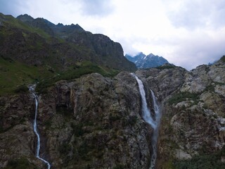 Obraz premium Aerial panorama of a Ushbi Waterfall among the Caucasian mountains, Stormy flow of mountain river Dolra. Summer vacation, hiking in Georgia