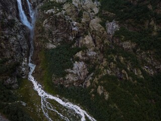 Aerial panorama of a waterfall among the high Caucasian mountains, Mount Ushba in the background. Valley in the city of Mazeri. Stormy flow of mountain river Dolra. Summer vacation, hiking in Georgia