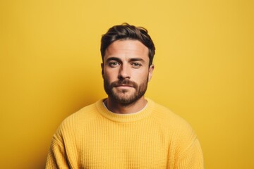 Fototapeta premium Portrait of a tender man in his 30s dressed in a warm wool sweater against a pastel yellow background. AI Generation