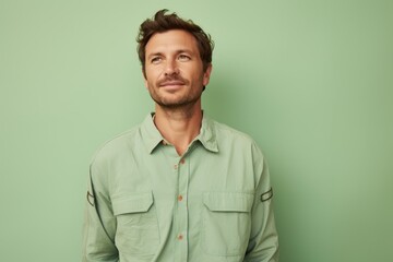 Obraz premium Portrait of a content man in his 30s sporting a vented fishing shirt against a pastel green background. AI Generation
