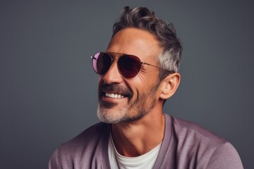 Obraz premium Portrait of a blissful man in his 40s wearing a trendy sunglasses against a pastel gray background. AI Generation
