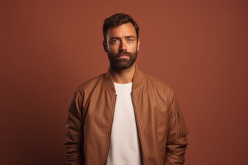 Fototapeta premium Portrait of a content man in his 40s wearing a trendy bomber jacket against a pastel brown background. AI Generation
