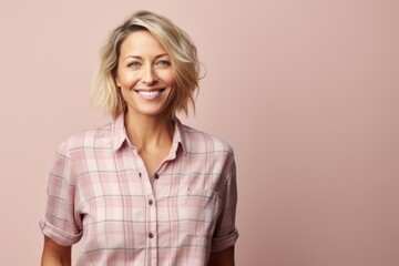 Portrait of a smiling woman in her 40s wearing a comfy flannel shirt against a soft pink background. AI Generation