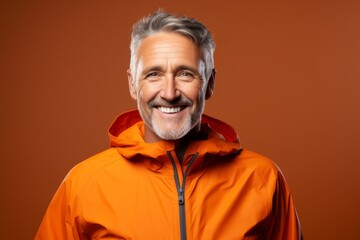 Portrait of a happy man in his 50s wearing a functional windbreaker against a soft orange background. AI Generation