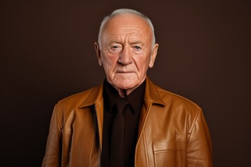 Portrait of a glad man in his 80s sporting a stylish leather blazer against a soft brown background. AI Generation