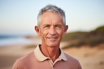 Portrait of a content man in his 60s wearing a breathable golf polo against a sandy beach background. AI Generation