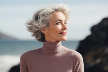 Portrait of a tender woman in her 50s wearing a classic turtleneck sweater against a serene seaside background. AI Generation