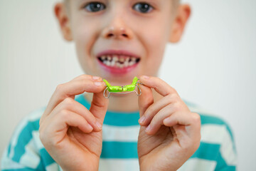 A blond-haired boy inserts orthodontic plate into his mouth to expand jaw and teeth. Close-up....