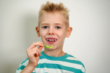 A blond-haired boy inserts orthodontic plate into his mouth to expand jaw and teeth. Close-up....