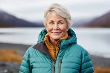 Portrait of a content woman in her 60s donning a durable down jacket against a beautiful lagoon background. AI Generation