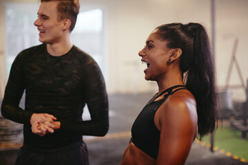 Fit young woman laughing with a friend at the gym