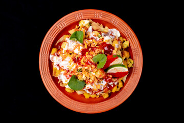 Indian dish mixed savory snacks, chanachur, mixed namkeen in mud plate on black background