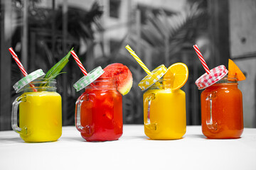 Multiple Juice Jar on a White Table including Papaya, Orange, Watermelon, and Pineapple Juice.