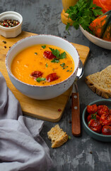 Plate with pumpkin puree soup and cherry tomatoes on a dark background