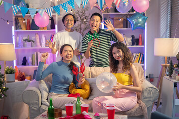 Fototapeta na wymiar Christmas party or celebrating New year 2024,Group of young adult Asian people having fun in living room celebrating Christmas eve together.Young Asian Friends cheering drinking celebrating Christmas 
