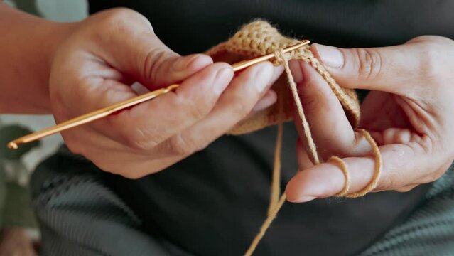 Close-up of hand woman holding crochet hook , enjoy knitting , sit on garden chair. hand of female knits handmade scarf at home, lady handwork craft hobby concept, 4k.