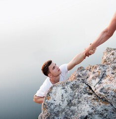 Man help his friend to climb on the rock