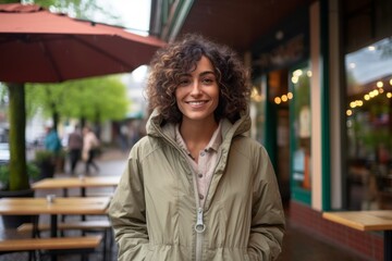 Fototapeta premium Portrait of a smiling woman in her 30s wearing a lightweight packable anorak against a serene coffee shop background. AI Generation