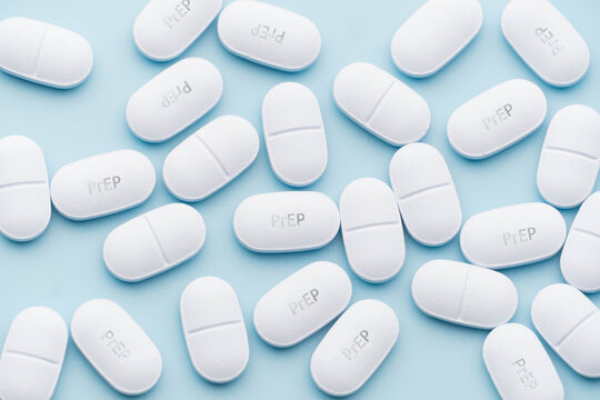 PrEP (Pre-Exposure Prophylaxis) tablets on blue background. Antiviral medicine used to prevent HIV infection.