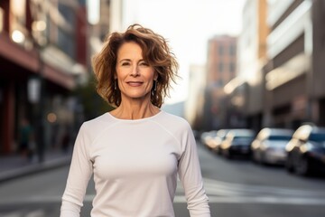 Portrait of a satisfied woman in her 50s sporting a long-sleeved thermal undershirt against a bustling city street background. AI Generation - obrazy, fototapety, plakaty