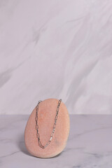 Silver jewelry chain on stone and natural flower, elegant gift