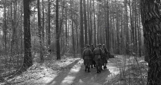 4K Squad Men Dressed As World War II Russian Soviet Red Army Soldiers Marching Through Spring Forest In Sunny day. Black And White Colors. Soldier Of WWII WW2 Times.