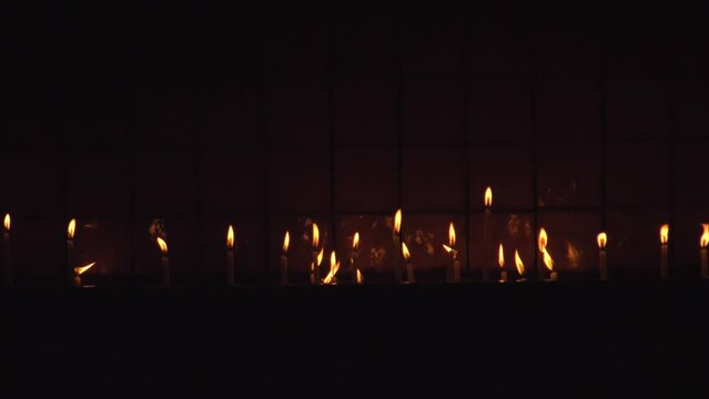 Burning candles in a Christian church in the dark. Slow motion