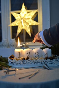 First Advent.  A woman lights the first of four candles with a match.  Tradition in Sweden before Christmas.