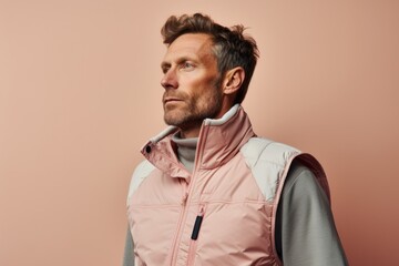 Portrait of a tender man in his 30s dressed in a water-resistant gilet against a pastel or soft...