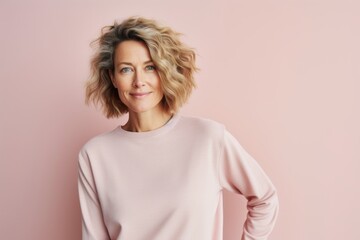 Portrait of a happy woman in her 40s showing off a thermal merino wool top against a pastel or soft...