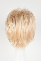 Naklejka premium Natural looking blonde fair wig on white mannequin head. Short hair cut on the plastic wig holder isolated on white background, back view.