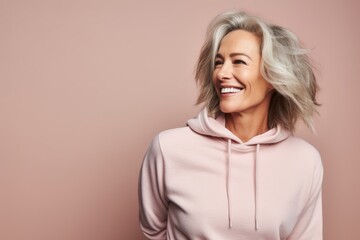 Portrait of a blissful woman in her 50s dressed in a comfy fleece pullover against a pastel or soft...
