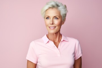 Portrait of a content woman in her 50s wearing a breathable golf polo against a pastel or soft...