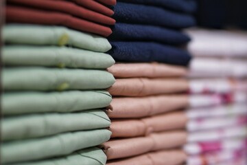 piles of colorful clothes neatly arranged on a clothing store shelf