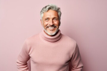 Obraz premium Portrait of a cheerful man in his 50s dressed in a warm wool sweater against a pastel or soft colors background. AI Generation