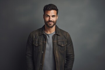Obraz premium Portrait of a tender man in his 30s sporting a rugged denim jacket against a minimalist or empty room background. AI Generation
