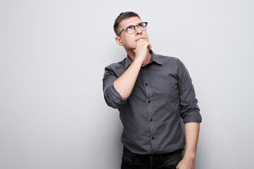 Fototapeta premium Portrait of clever man in shirt touching chin thinks doubts chooses isolated on white studio background with copy space