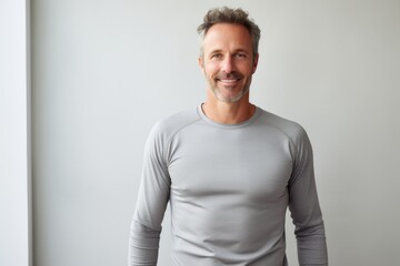 Portrait of a smiling man in his 40s showing off a lightweight base layer against a minimalist or empty room background. AI Generation