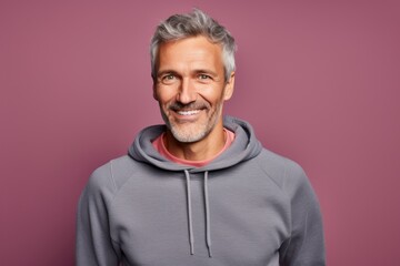 Portrait of a glad man in his 50s dressed in a comfy fleece pullover against a solid color...